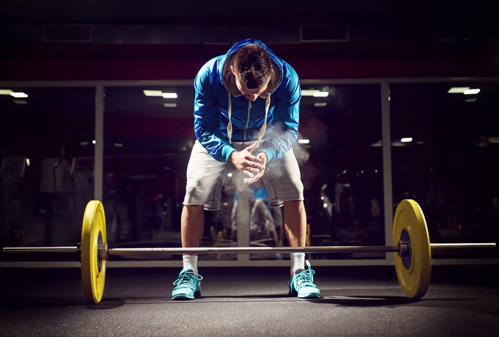 Cross fit weightlifter preparing for training. Shallow depth of